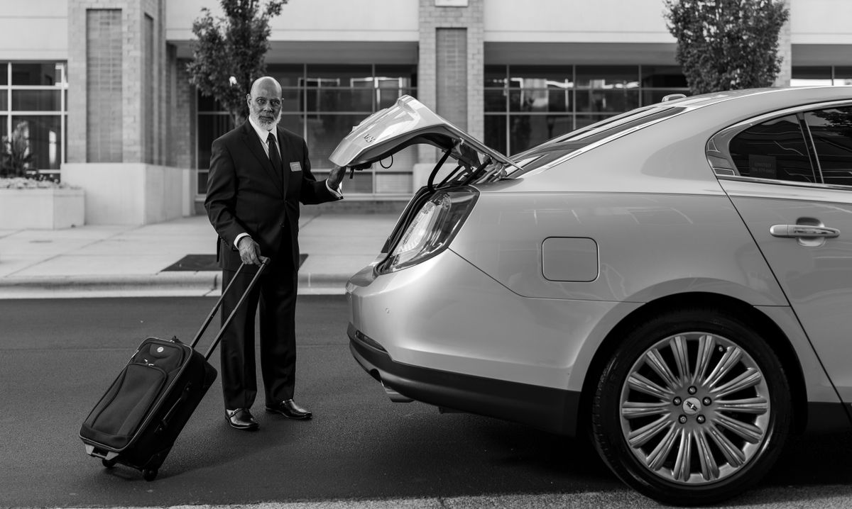 Professional driver assisting passenger with luggage for Toronto airport taxi service
